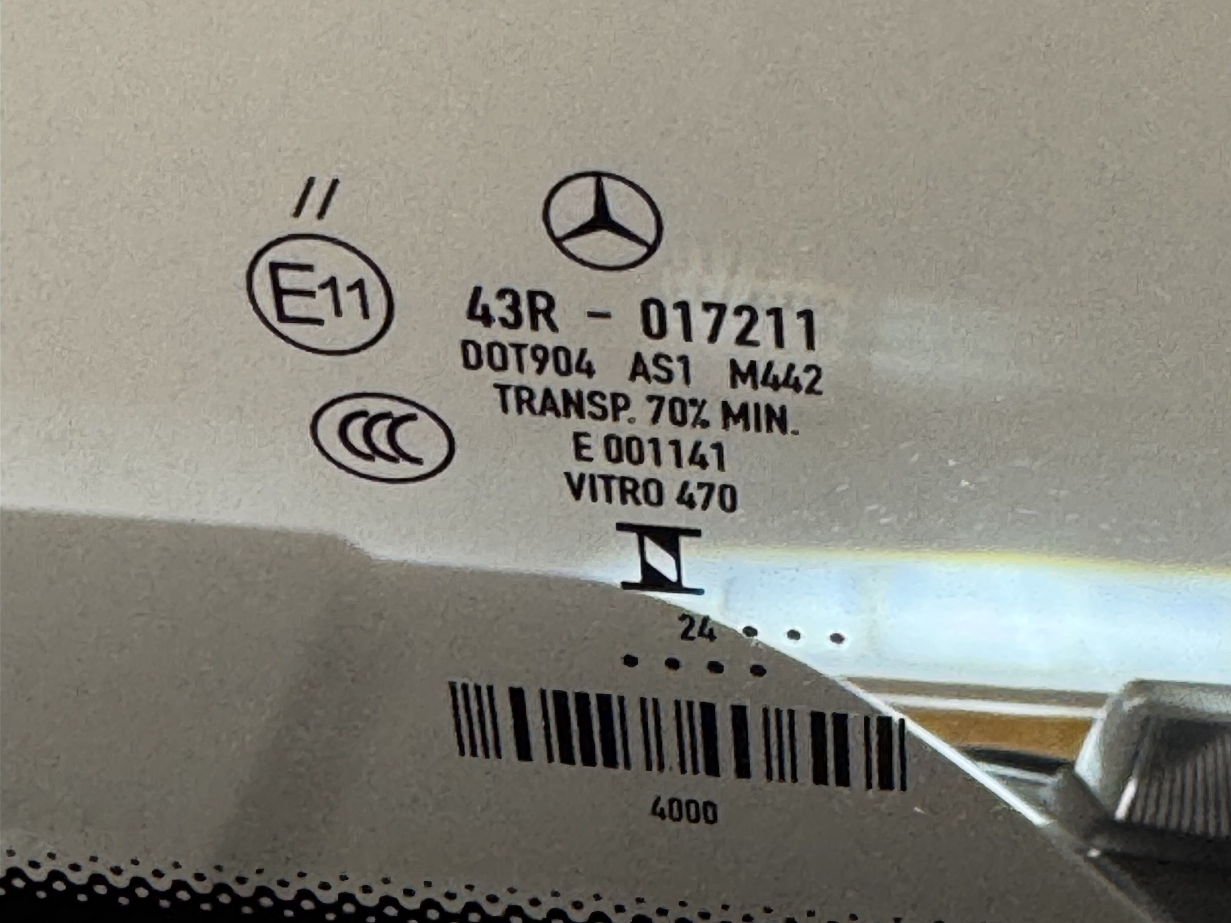 The bug etched into the installed windshield: Mercedes star, E11 43R-017211, DOT 904, AS1, M442, TRANSP 70% MIN, VITRO 470.